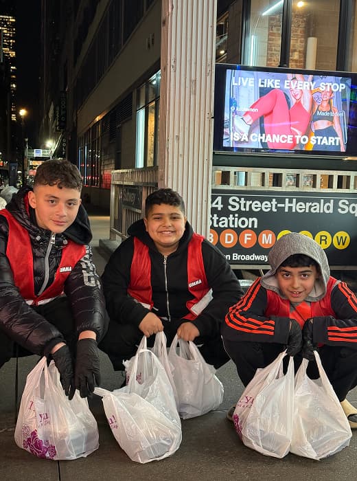 Queens distribution night, volunteers handing meals.